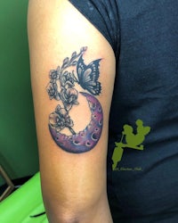 a tattoo with a butterfly and flowers on the arm