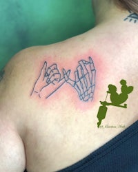 a woman's back with a tattoo of a skeleton and two hands